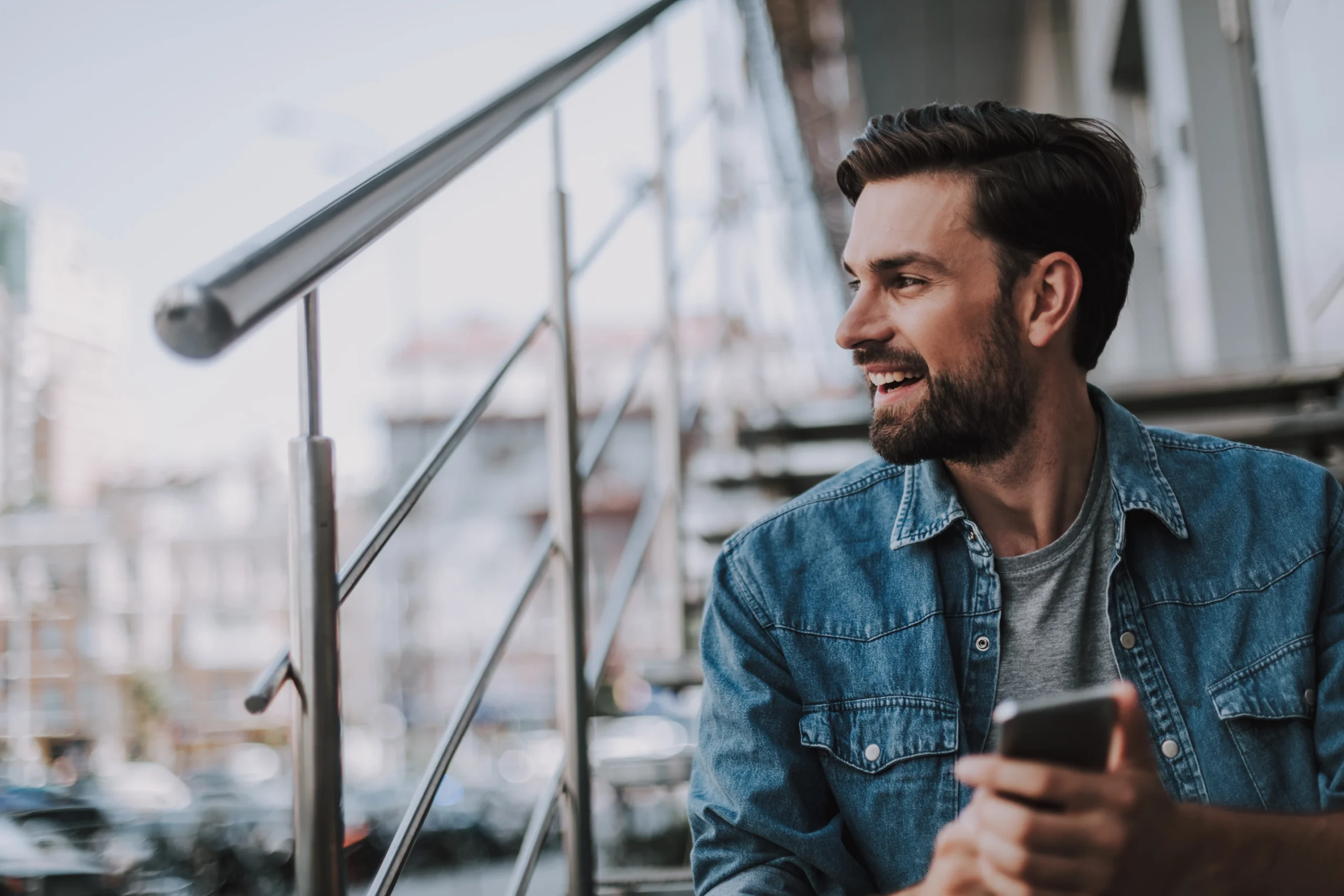 young adult sitting looking thought his balcony